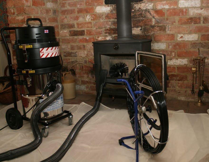 Professional chimney sweeping equipment set up in front of a wood burner